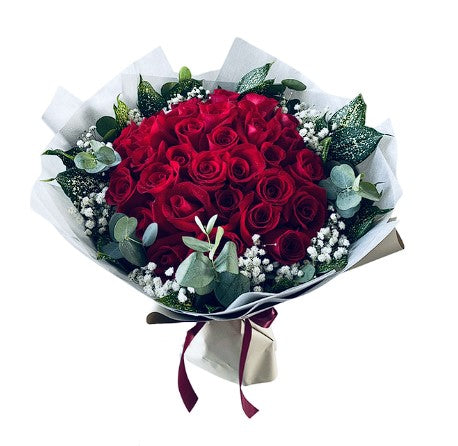 thirty six red roses and greenery wrapped in white wrapping paper and red ribbon for a gorgeous luxurious bouquet