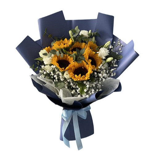 Bouquet of sunflowers and white flowers wrapped in blue paper with a white ribbon on a white background